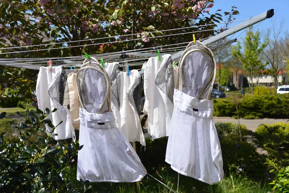 Imker met hoofdbescherming bij de bijenkasten